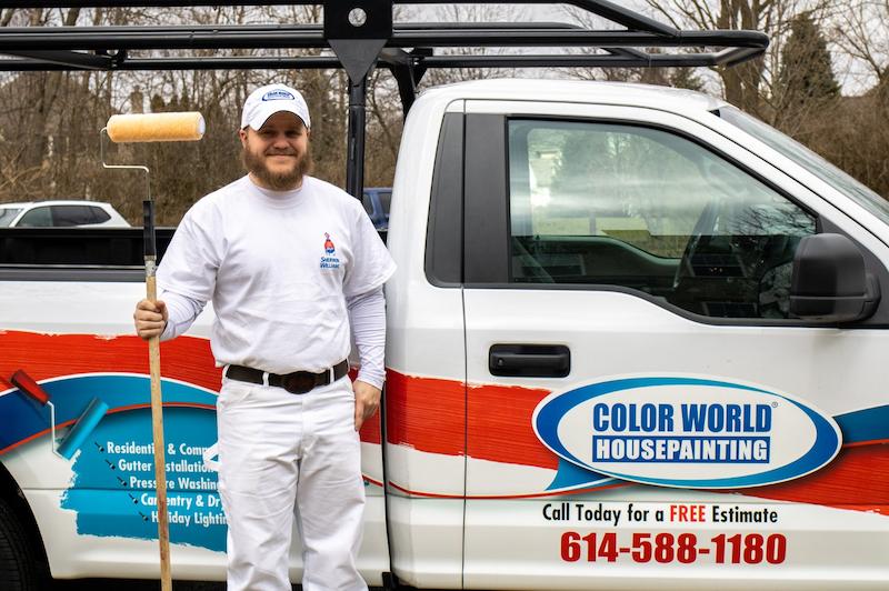 Color World house painter standing in front of truck holding tall paint roller